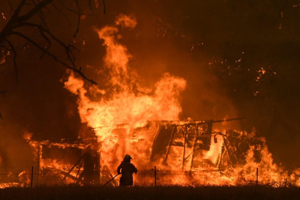 In this Dec. 21, 2019, file photo, NSW Rural Fire Service crews fight the Gospers Mountain Fire as it impacts a structure at Bilpin, Australia.