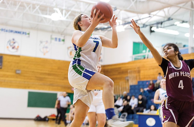 Citizen Photo by James Doyle. Kelly Road Roadrunners player Carley Gurney goes for a lay-up against a North Peace Grizzlies defender on Friday evening at Kelly Road Secondary gymnasium during the Kelly Road Sr. Girls Invitational basketball tournament.