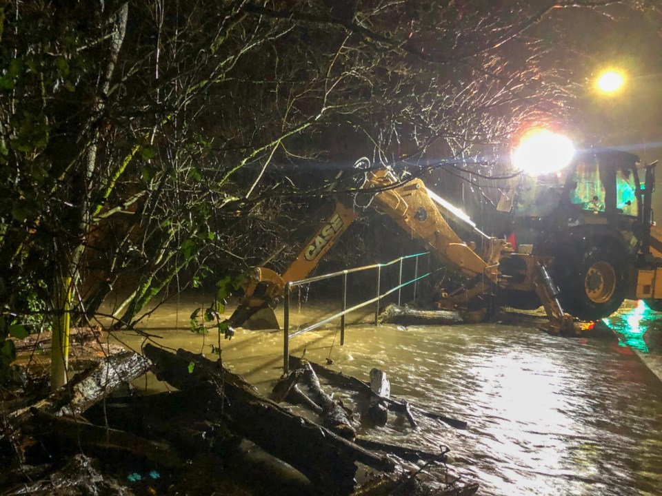 A backhoe from Port Coquitlam public works tries to dislodge debris from a flooded culvert as floodi