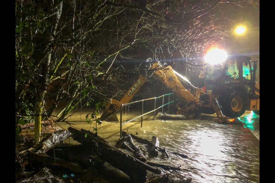 A backhoe from Port Coquitlam public works tries to dislodge debris from a flooded culvert as flooding from Hyde Creek spills into six homes along Coast Meridian Road, including one which doubles as a daycare.