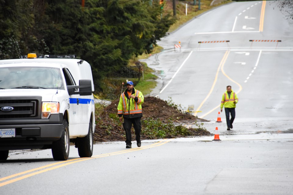 Workers from the city of Coquitlam assess a landslide triggered by torrential rains along Pipeline R