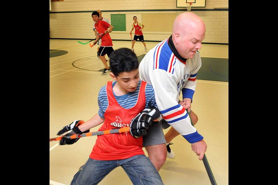 Arya Ardehali challenges an RCMP officer for the ball in the exhibition game to launch the School Sports program.
