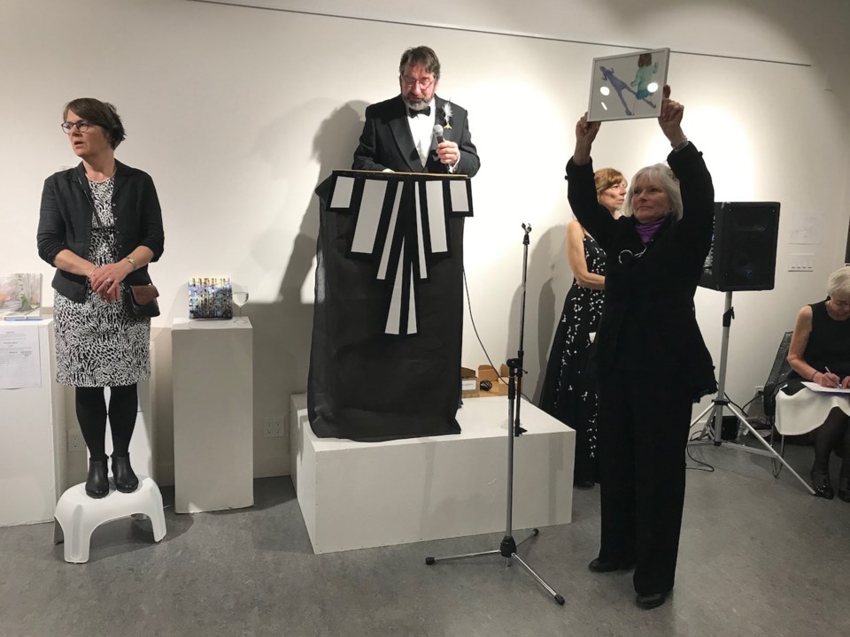 Anne Boa holding up a painting and three folks stand in the background at last year's mini gala