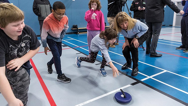 Citizen Photo by James Doyle. Olympic curler Karri Willms helps the kids do some floor curling at Harwin Elementary School during a learn-to-curl session on Friday morning.