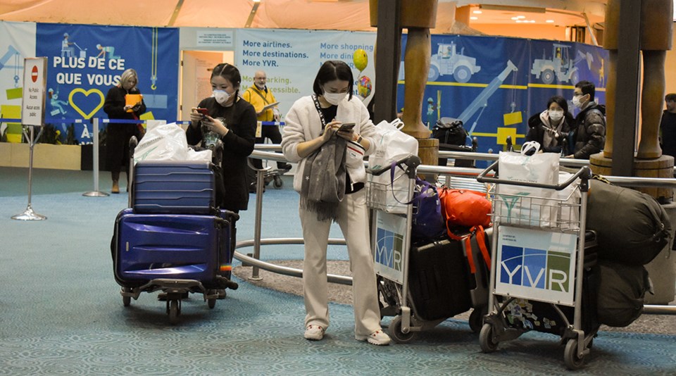 Travellers at Vancouver International Airport wear masks