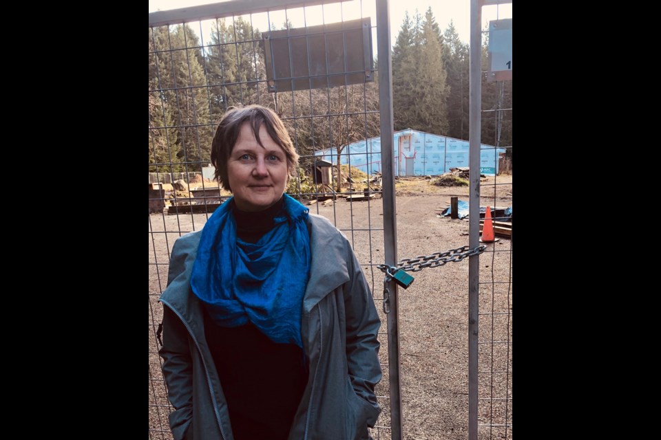 Florette MacLean in front of the fenced-off remains of the Hornby Island school damaged by fire in August 2018. A Times Colonist Literacy Fund grant will help restock the library.