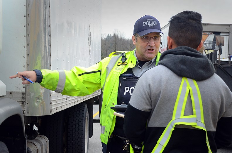 An RCMP officer talks to a truck driver at a commercial vehicle check on Gaglardi Way Tuesday.