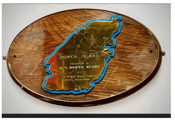 Bowen-shaped gold-coloured plaque mounted on wood.