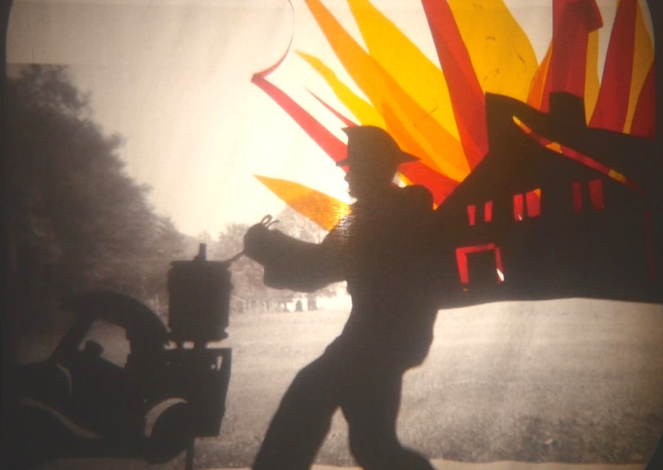 Still frame of shadow puppet firefighter a building in apparent (shadow) flames in the background.