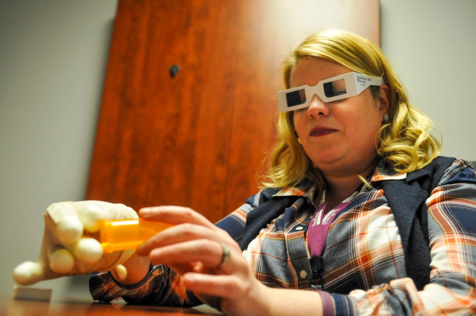 Home Instead Senior Care's Mandi Strickland attempts to remove pills from a medicine bottle