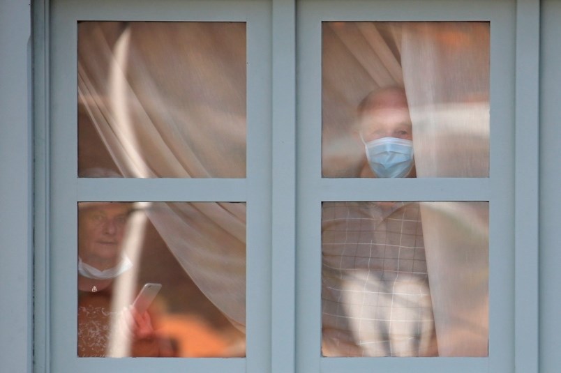 People look through a window of the H10 Costa Adeje Palace hotel in La Caleta while under lock down