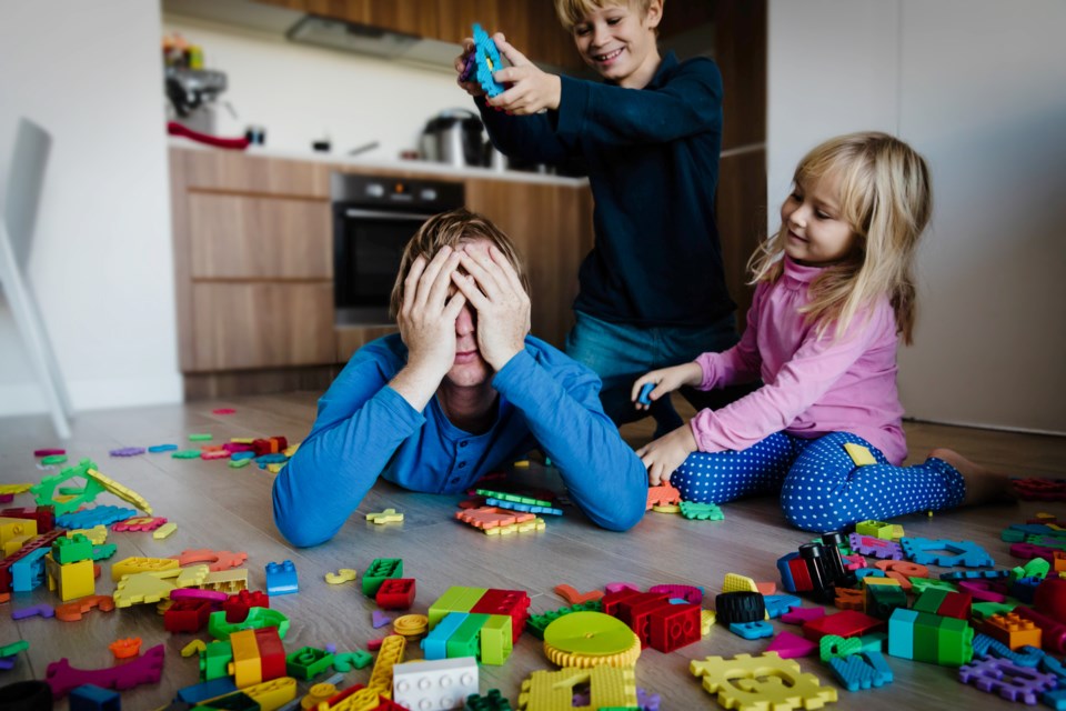 tired parent surrounded by children with toys