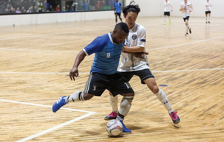 Thierry Mboneko of Team India holds off the check of Kensho Ando of Team South Korea while trying to clear the ball out of the defensive end during Sunday's men's division final at the World Cup Indoor Soccer Tornament at the Prince George Dome. South Korea won 5-3.