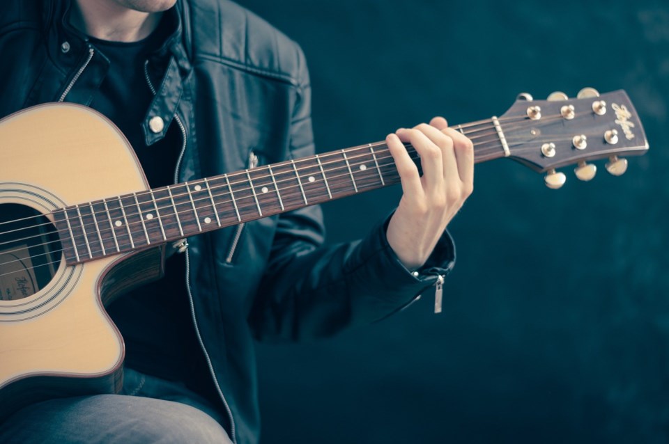 Fellow playing the guitar with a black background