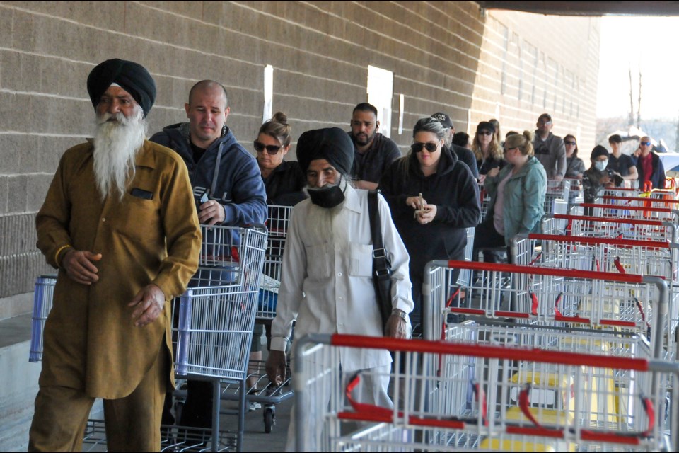 Customers queue at the Costco in Port Coquitlam. The grocery chain has instituted a cap on shoppers inside at any given time so as to maximize social distancing.