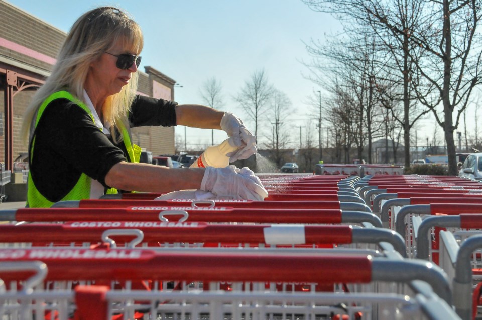 A Costco employee disinfects shopping carts in Port Coquitlam. The Tri-City's branch of the grocery