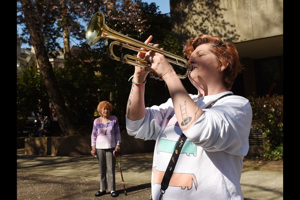 Samantha Monckton plays her trumpet Wednesday in front of her father’s long-term care home, as resident Margaret Holtz looks on. Monckton's father, Garry, has tested positive for COVID-19. Photo Dan Toulgoet