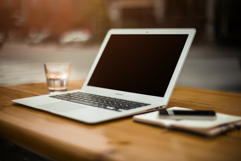 A computer, glass and pen on a desk