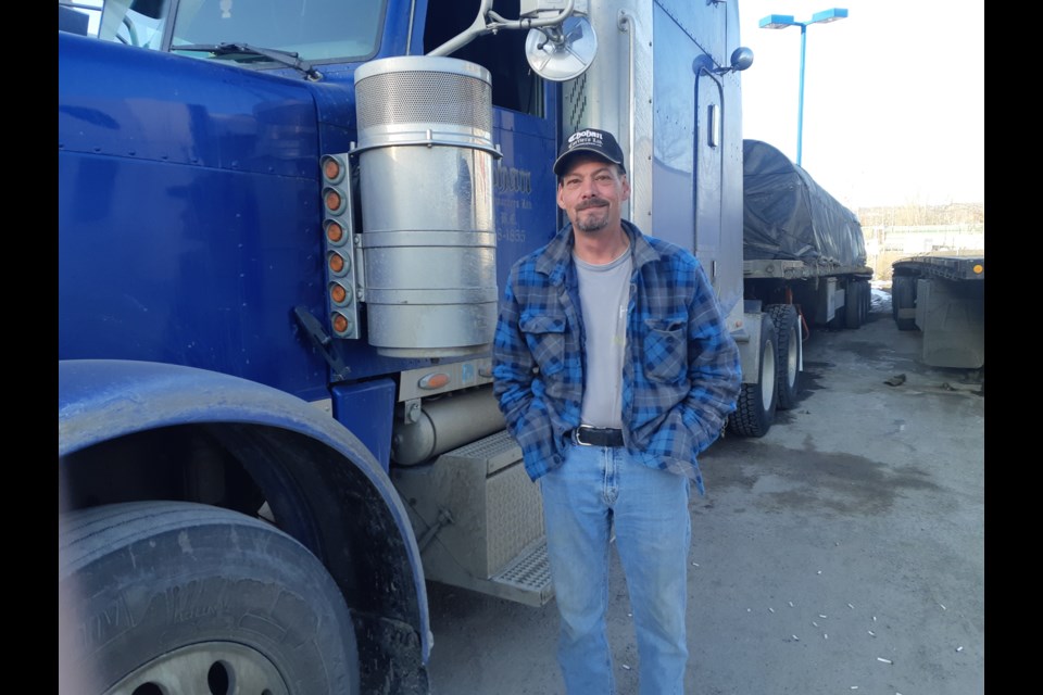 Mike Augustino of Calgary stands by his truck at the Prince George Husky/Esso Travel Centre along Highway 97 South. The highways have been quiet lately with everybody hunkered down because of the COVID-19 pandemic and like other truckers he's finding it more difficult to get a cup of coffee and homecooked meal when he's on the road.
