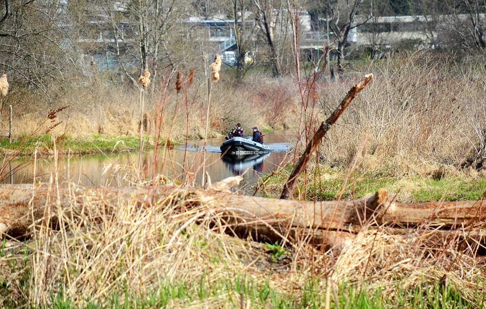 Two Burnaby firefighters and an RCMP officer search Burnaby Lake Monday after an empty canoe and two oars were found floating on the water.