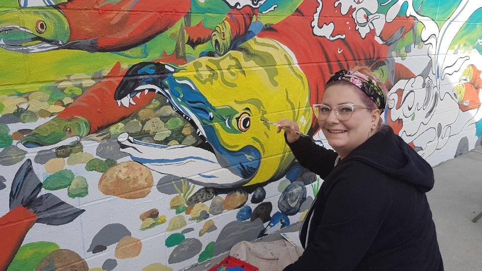 Teacher and mural artist Shannon Thiesen at work on the mural at the pool at Aggie Park.