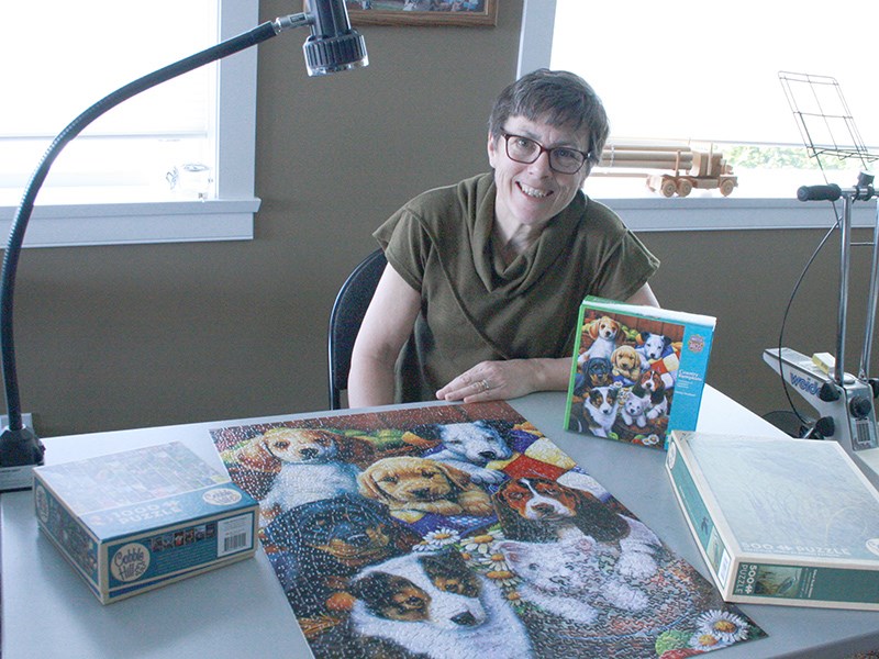 PUZZLE PERSON: Anne Baker is one of many Powell River residents who finds relaxation and enjoyment from jigsaw puzzles. Baker considers doing a puzzle like exercise for her brain, and will continue to work on it even if the pattern is more difficult, like the completed puzzle pictured. Vanessa Bjerreskov photo