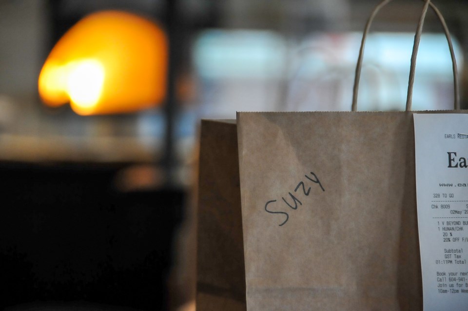 Take-out orders litter the tables of the empty restaurant where customers once sat.