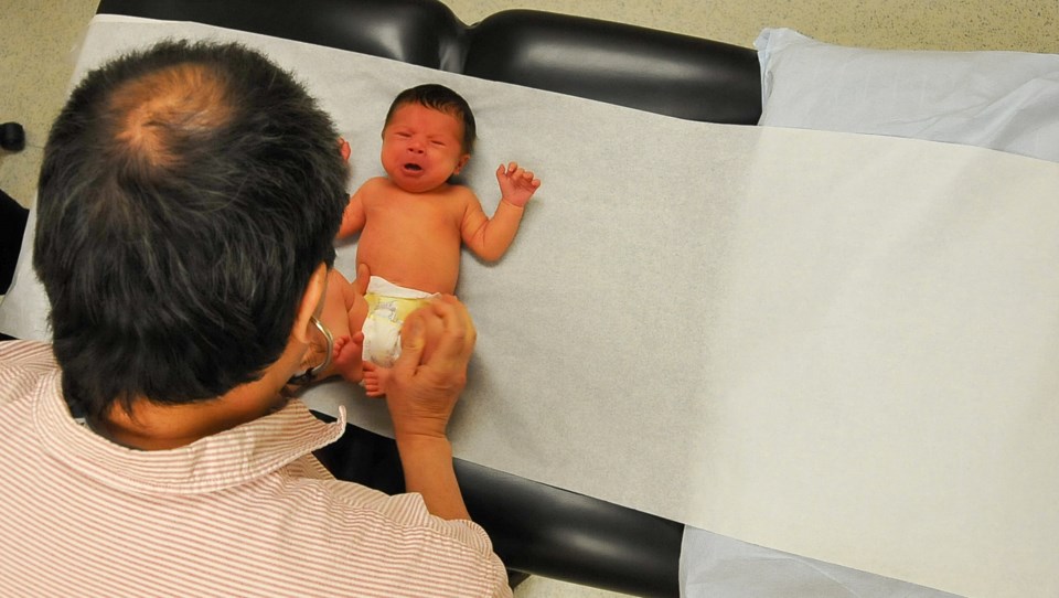 Newborn Elizabeth Ten has her joints examined by Dr. Grover Wong.