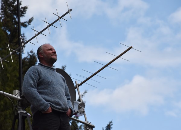 Scott Tilley looks in the direction of the LES-5, next to the antenna he constructed and installed on the roof of his home in Roberts Creek.