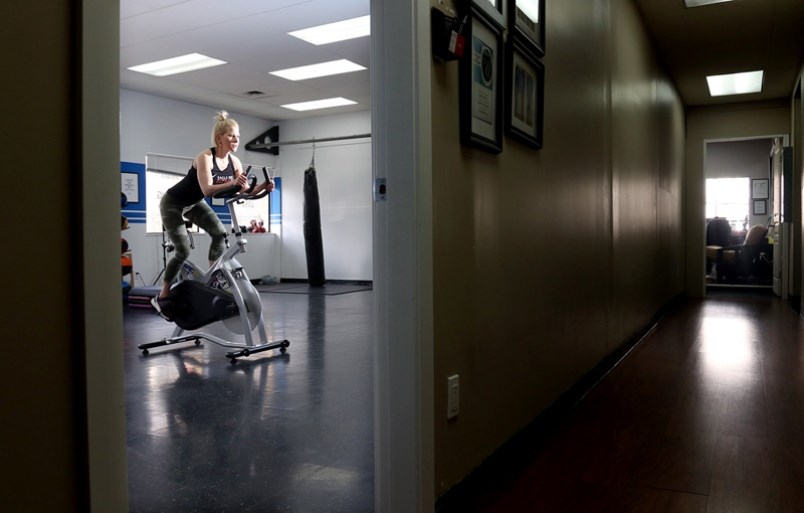 Laurie Elizabeth Noh works out on a spin bike at the Port Coquitlam fitness studio she operates with her husband, Sam. The Nohs, who own Eagle Ridge Fitness, in PoCo and Port Moody, are ready to work with clients in small groups or individually but are waiting for permission from Fraser Health.