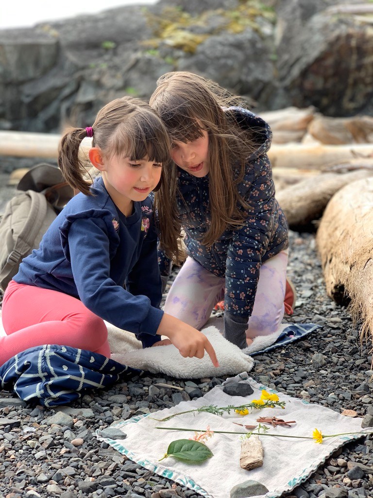 Kids on the beach looking at flowers, pebbles and other beachly items