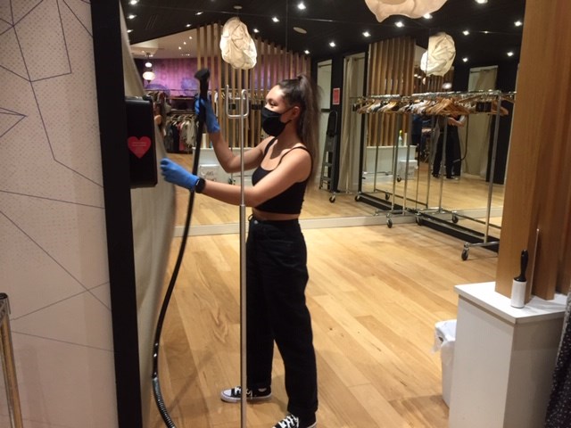 Kim Turnbull uses a steam cleaner on clothes after a customer tries them on at Plenty at Coquitlam Centre. High temperatures from a steam blast are supposed to kill the coronavirus.