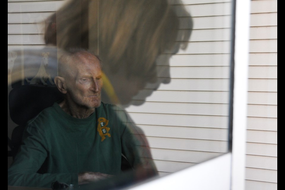 Brigitte Beurmann waves to her husband Bernie, who suffers from vascular dementia and lives under lockdown at a long-term care home in Port Coquitlam. Brigitte has visited Bernie every day since the pandemic lockdown began, and worries that by the time the measures are lifted, he won't recognize her at all.