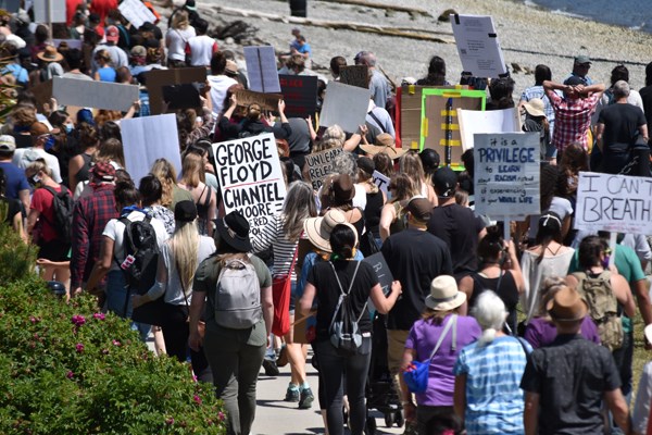 People walk along the waterfront in Sechelt as part of a protest against racism.