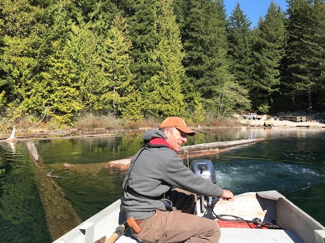 Alistair McCrone driving the boat towing a log at Cat Lake.