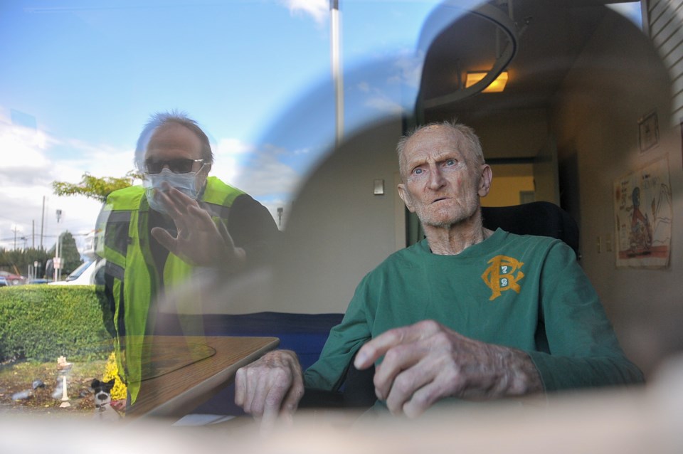 James Beurmann waves to his father Bernie through the glass at Port Coquitlam's Hathorne Seniors Car