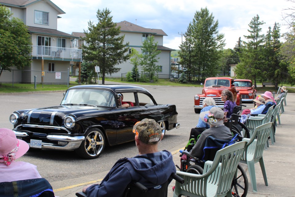 Dwayne Harvey, in his black 1955 Pontiac, drives by residents of the Gateway Lodge assisted-living seniors home Friday afternoon. The seniors tour of about 60 classic vehicles visited seven long-term residences.