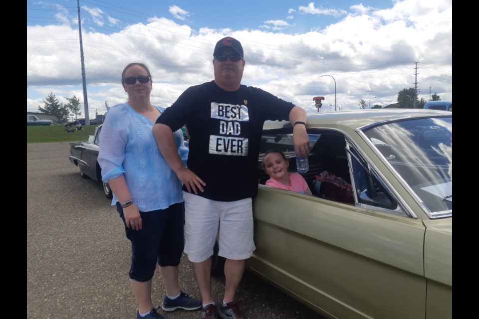 Elizabeth and Mark Lawrence stand next to their 1965 two-door Mustang, while their eight-year-old daughter Victoria waits in the back seat to get started in Sunday's Cruisin' Classics COVID Cruise for a Cause. More than 300 vehicles took part in the event, which raised $5,311 for the Salvation Army Food Bank.