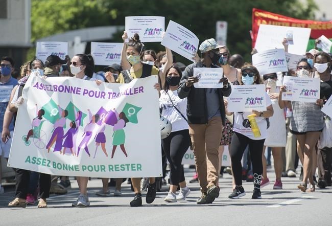 People hold up signs during a demonstration outside Prime Minister Justin Trudeau's constituency off