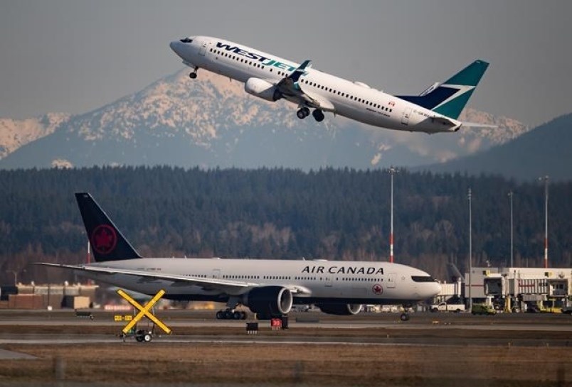 An Air Canada flight departing for Toronto, bottom, taxis to a runway as a Westjet flight bound for