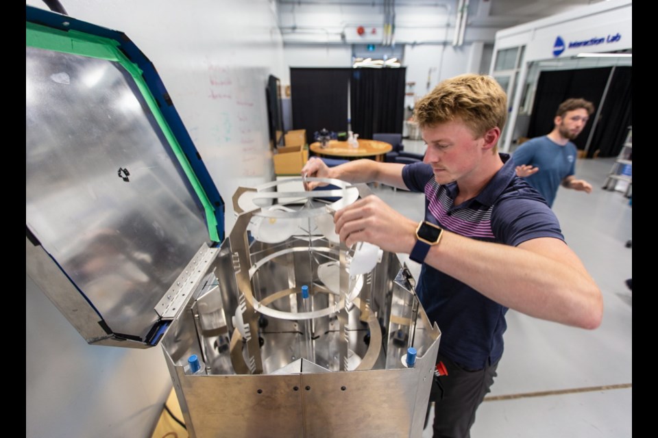 Camosun College 2nd year mechanical engineering student Cody Short loads a new oven, called a UVen, developed to disinfect N95 masks for reuse.
