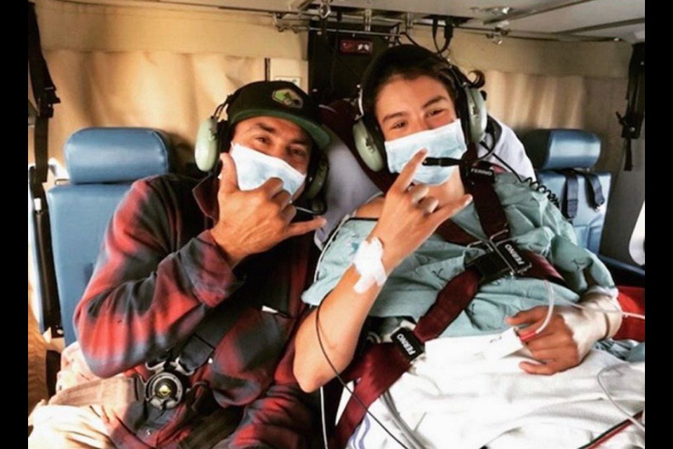 The North Vancouver teen who was rescued by his friend while surfing in Tofino, with his father. The 15-year-old has asked that his name not be used.