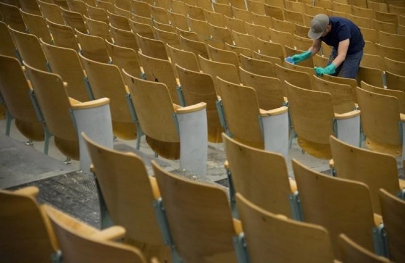 A worker cleans the seats of the auditorium at Eric Hamber Secondary school in Vancouver, B.C., Mond