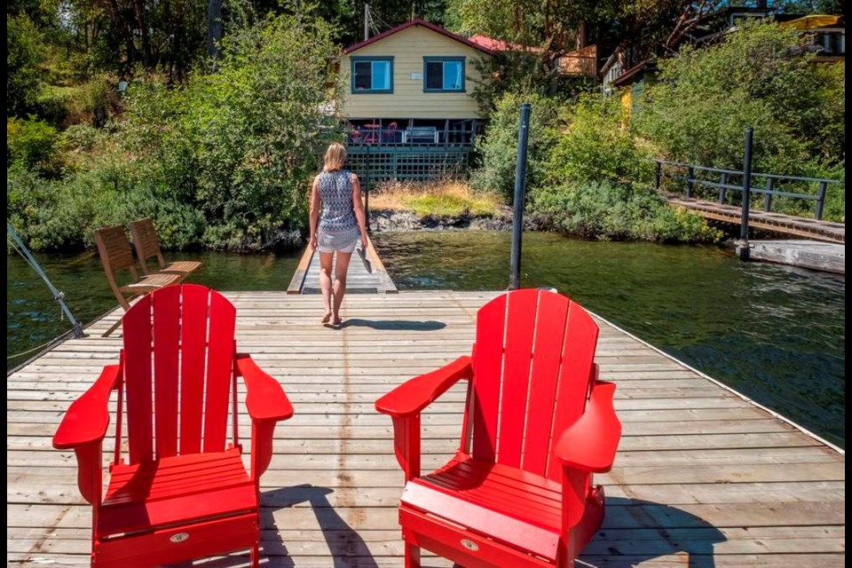 Bright red Muskoka chairs provide an ideal seating spot on one of the two docks at Vintage Cabins. In the distance, the Birdhouse, which has been freshly painted with historic colours from Benjamin Moore, can be seen. DEBRA BRASH