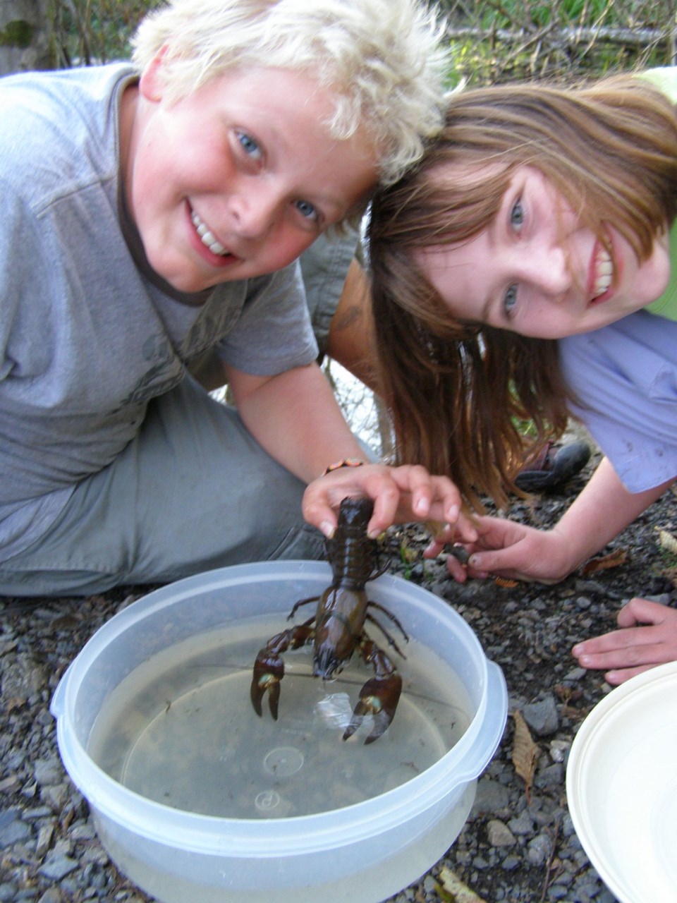 Two kids holding a signal crayfish