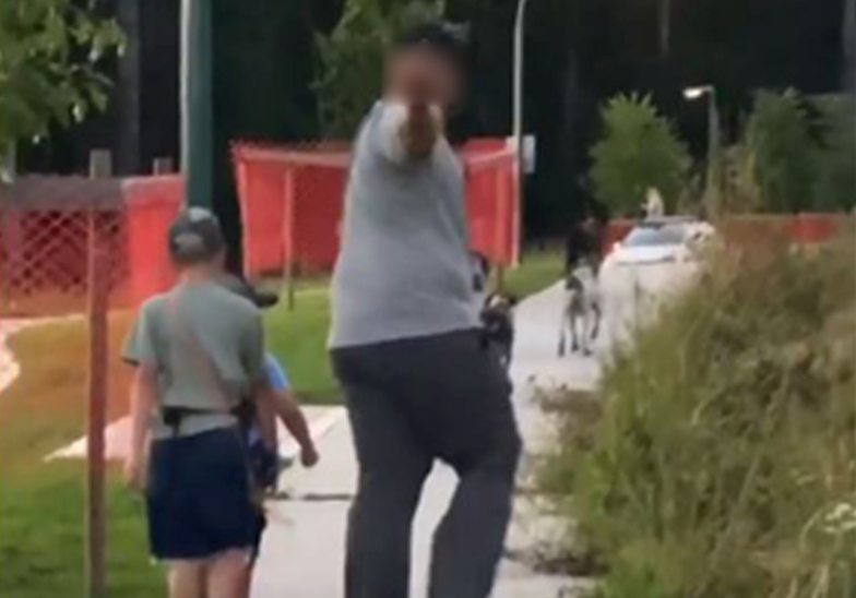 A man turns around and gestures to the couple with the injured dog