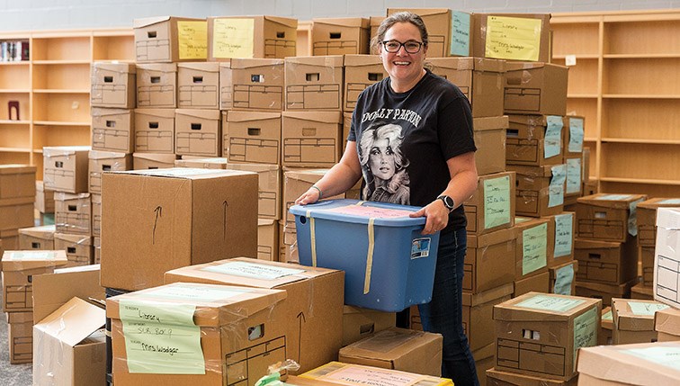 Citizen Photo by James Doyle. Librarian Rhea Woolgar stands among the boxes of learning materials in the library at the new Shas Ti Kelly Road Secondary School on Monday morning during a media tour. Nearly 1500 boxes of learning materials will need to be moved, unboxed, sorted, and put on shelves in the library before the start of the school year.