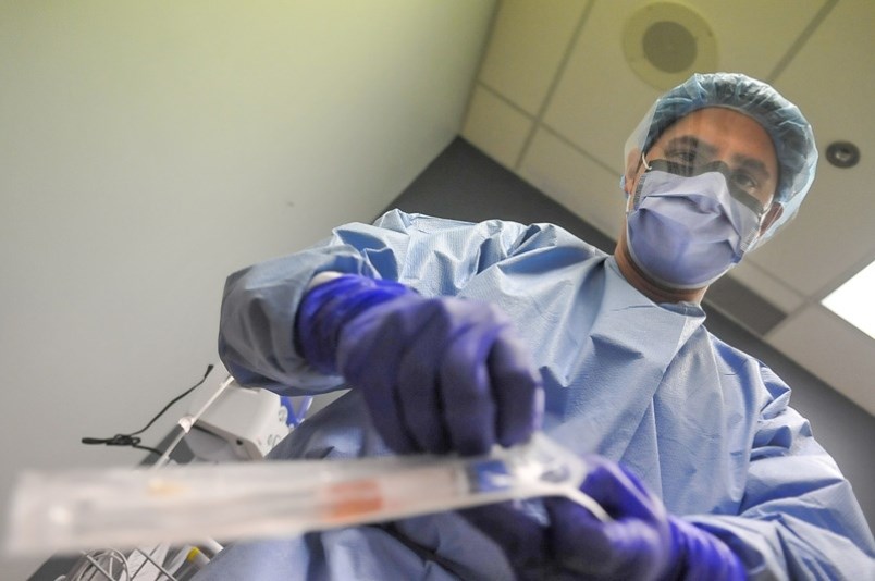 Dr. Ali Okhowat of Coquitlam prepares a pharyngeal swab kit at a COVID-19 clinic in New Westminster.