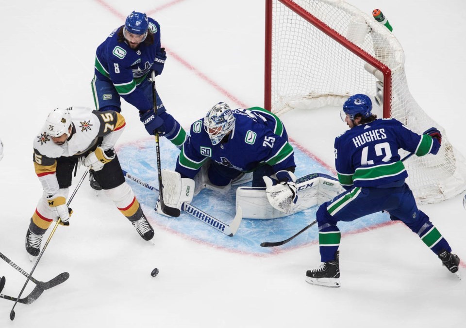 Quinn Hughes, Chris Tanev, and Jacob Markstrom defend the Canucks net, with Ryan Reaves of the Vegas