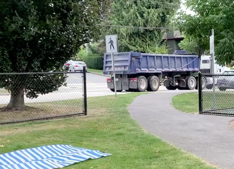 Truck backs up over a crosswalk near a picnic area